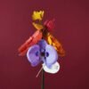 Bouquet de fleurs artisanales en papier d'art coloré, orchidée violette et pavot corail, présenté dans un vase noir sur fond bordeaux. Note : C'est ce qui aide Google Images à comprendre le contenu de la photo et améliore l'accessibilité.