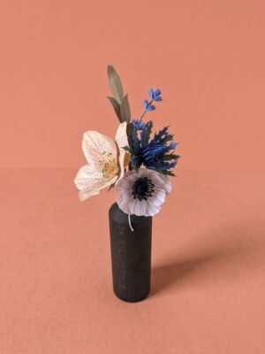 Petit bouquet de fleurs en papier d'art avec une hellébore ivoire, une anémone rose pâle, un chardon bleu, de la mini lavande et du mini olivier, dans un vase en bois sombre