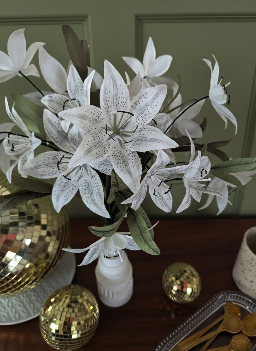 Détail d'un bouquet de lys en papier, mettant en avant le Mini Lys Stargazer au cœur ton-sur-ton, sans feuillage, à côté d'une boule disco dorée.