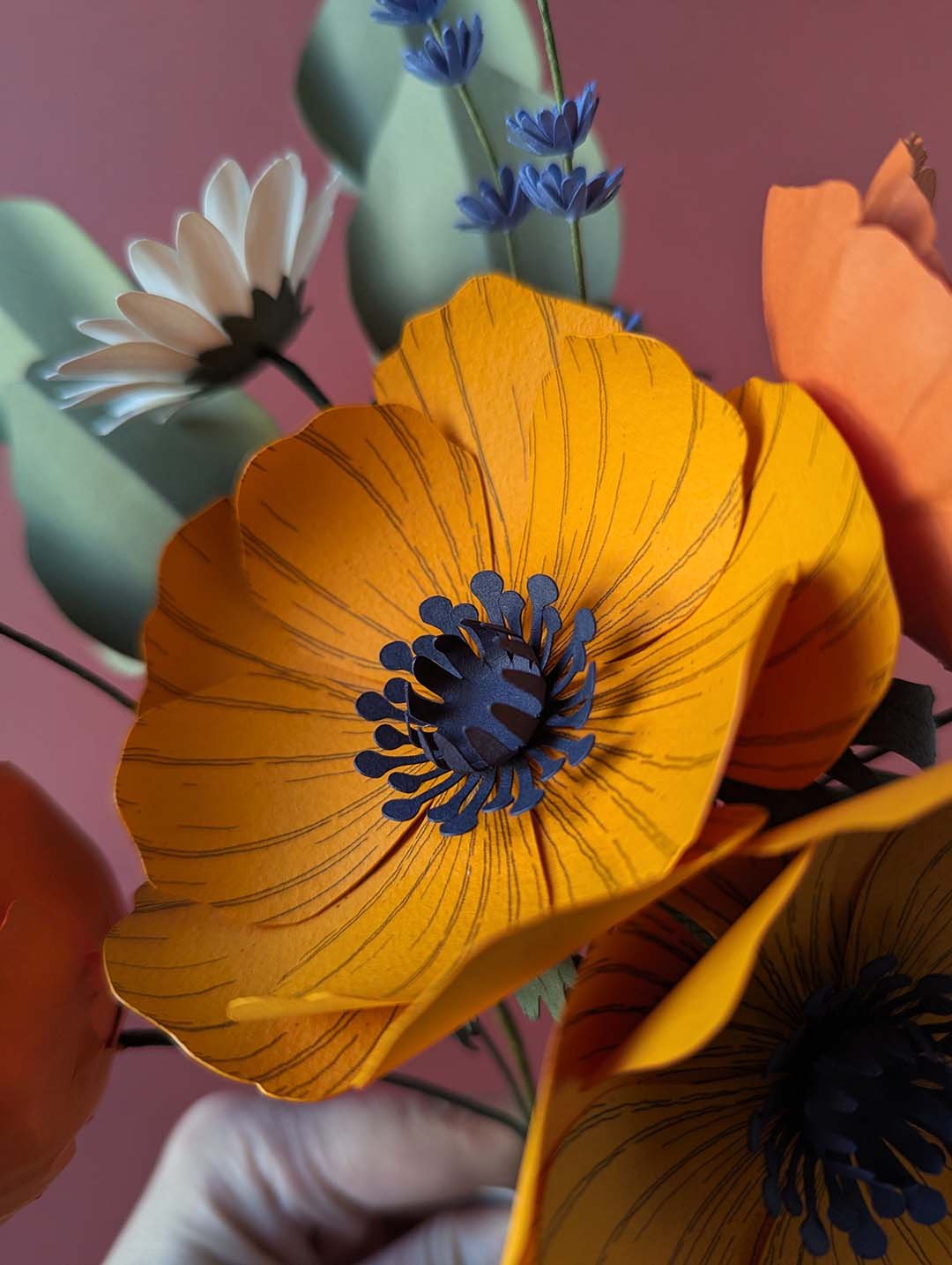 Gros plan sur une grande anémone jaune soleil aux nervures dessinées à la main et au cœur bleu nuit du bouquet Garrigue en fleurs de papier artisanales