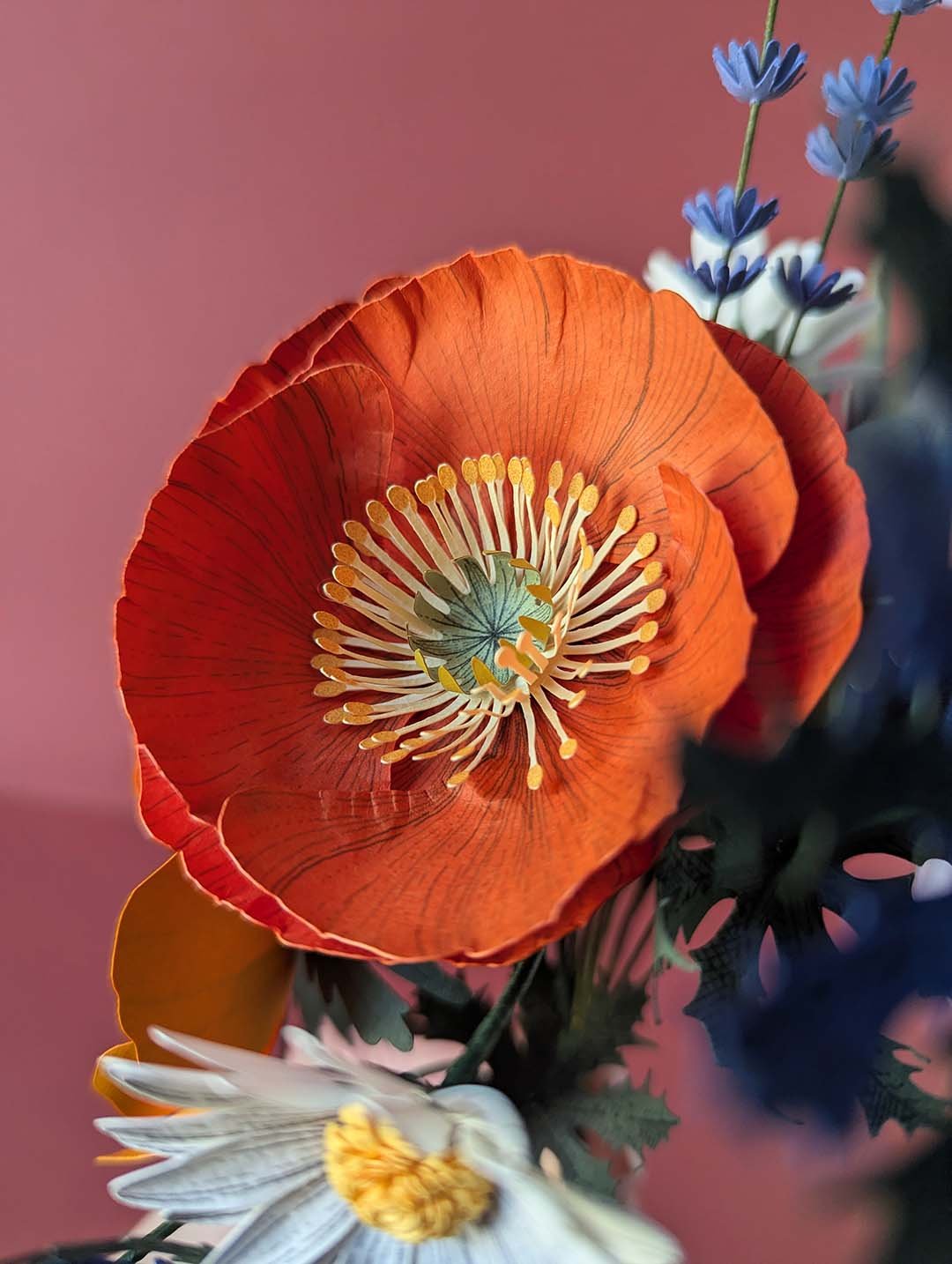 Gros plan sur le grand pavot orange du bouquet Garrigue en fleurs de papier, pétales rouge orangé nervurés ouverts, avec étamines en papier jaune or au centre