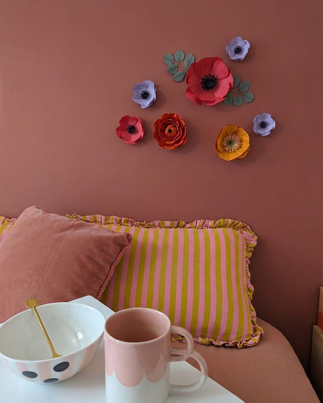 Fleurs murales aimantées colorées en décoration dans une chambre sur mur rose vénitien avec lit et accessoires