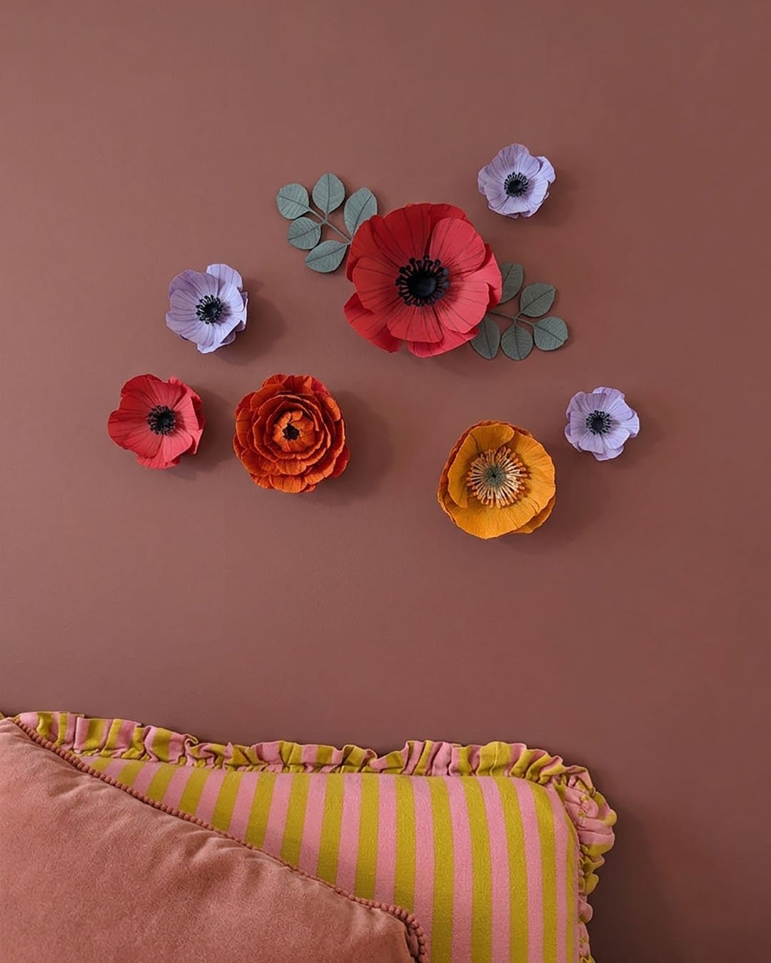 Fleurs murales aimantées colorées au-dessus d’un lit dans une chambre avec oreillers pour montrer l’échelle