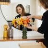 Anaïs LVDX arrange à la main son bouquet de fleurs en papier Masterpiece Orange dans un vase vert kaki, reflet dans un miroir rond