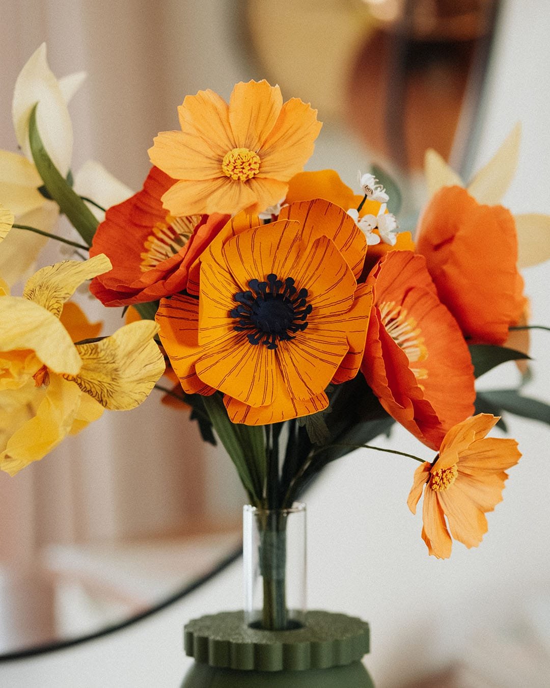 Vue rapprochée du bouquet Masterpiece Orange avec grande anémone jaune soleil au premier plan, pavots orange et iris bouton d'or, fleurs en papier artisanales