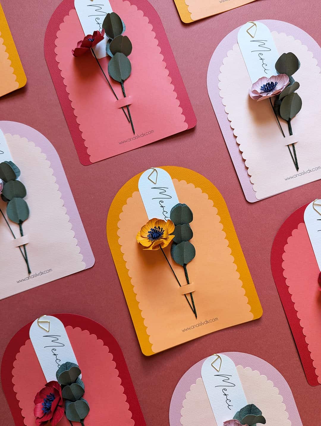 Vue d'atelier des cartes fleuries Merci Fleuri collection Éclore, trois coloris disposés en perspective Légende : Dans l'atelier — collection Éclore en trois coloris