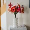 Bouquet artisanal de fleurs en papier d'art Masterpiece Rose dans un vase blanc posé sur une pile de livres, décoration intérieure slow living, Anaïs LVDX