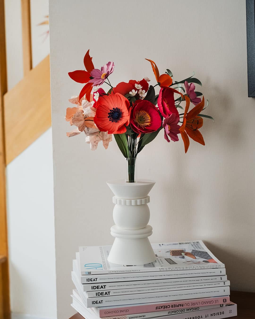 Bouquet artisanal de fleurs en papier d'art Masterpiece Rose dans un vase blanc posé sur une pile de livres, décoration intérieure slow living, Anaïs LVDX