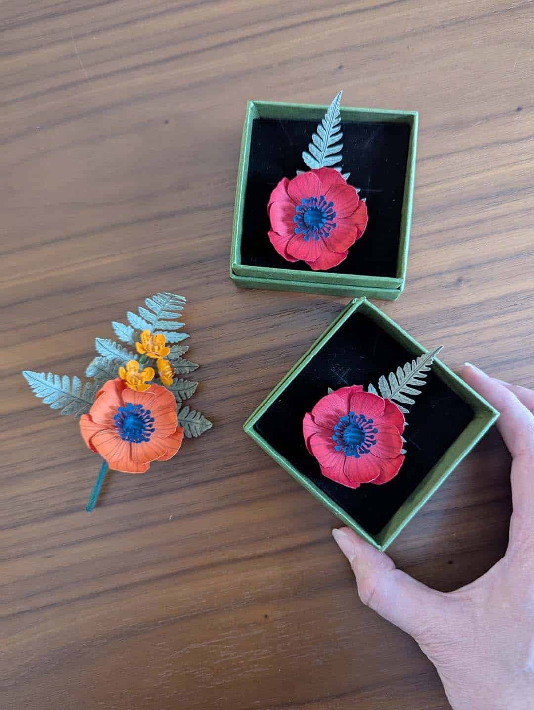 Broches fleuries fleurs en papier anémone rouge dans leurs coffrets pour cortège de mariage