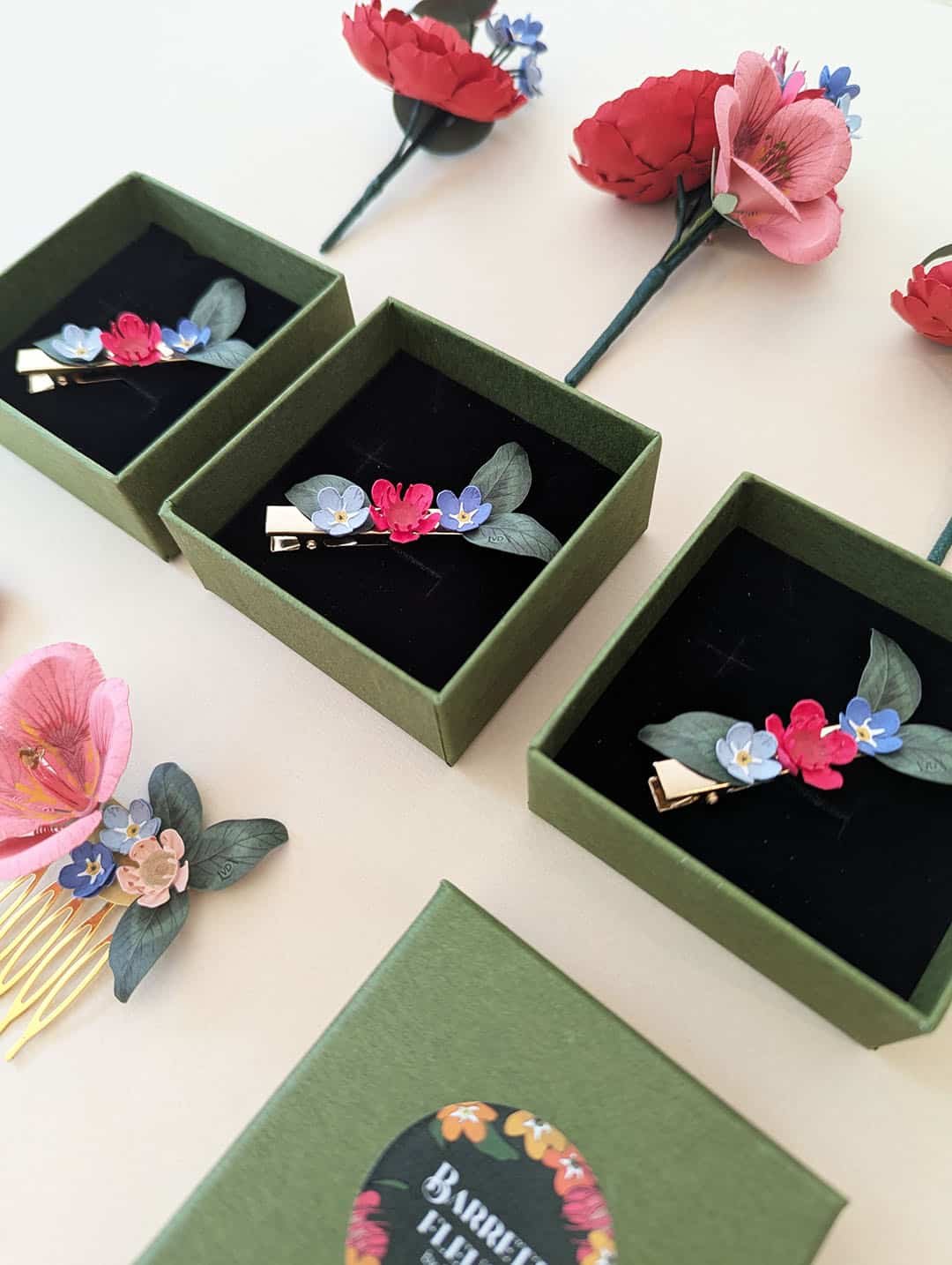 Trois barrettes fleuries en fleurs de papier dans leurs coffrets pour cortège de mariage