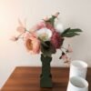 Gros plan sur un bouquet de fleurs en papier avec une pivoine rosa, un pavot blanc et des leucospermums rose vénitien
