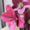 Gros plan sur une tulipe fuchsia ouverte et des hellébores viola en papier d'art, avec un œillet rosa au second plan