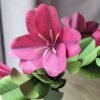 Tulipe fuchsia ouverte en papier d'art posée sur des feuilles de grand eucalyptus pistache, dans le bouquet Léo