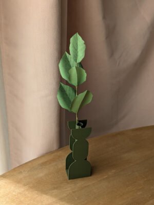 Branche de hêtre en papier coloris vert pomme dans un vase vert imprimé en 3D sur une table en bois