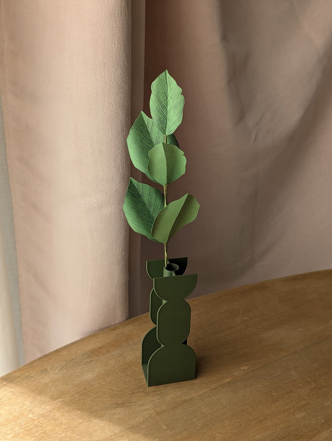 Branche de hêtre en papier coloris vert pomme dans un vase vert imprimé en 3D sur une table en bois
