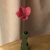 Tulipe ouverte en papier coloris fuchsia dans un vase vert sur une table en bois
