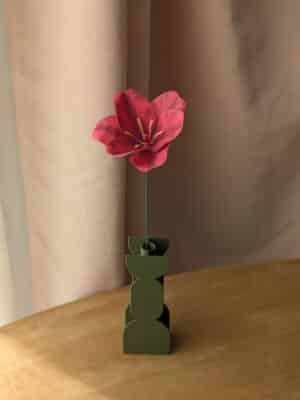 Tulipe ouverte en papier coloris fuchsia dans un vase vert sur une table en bois