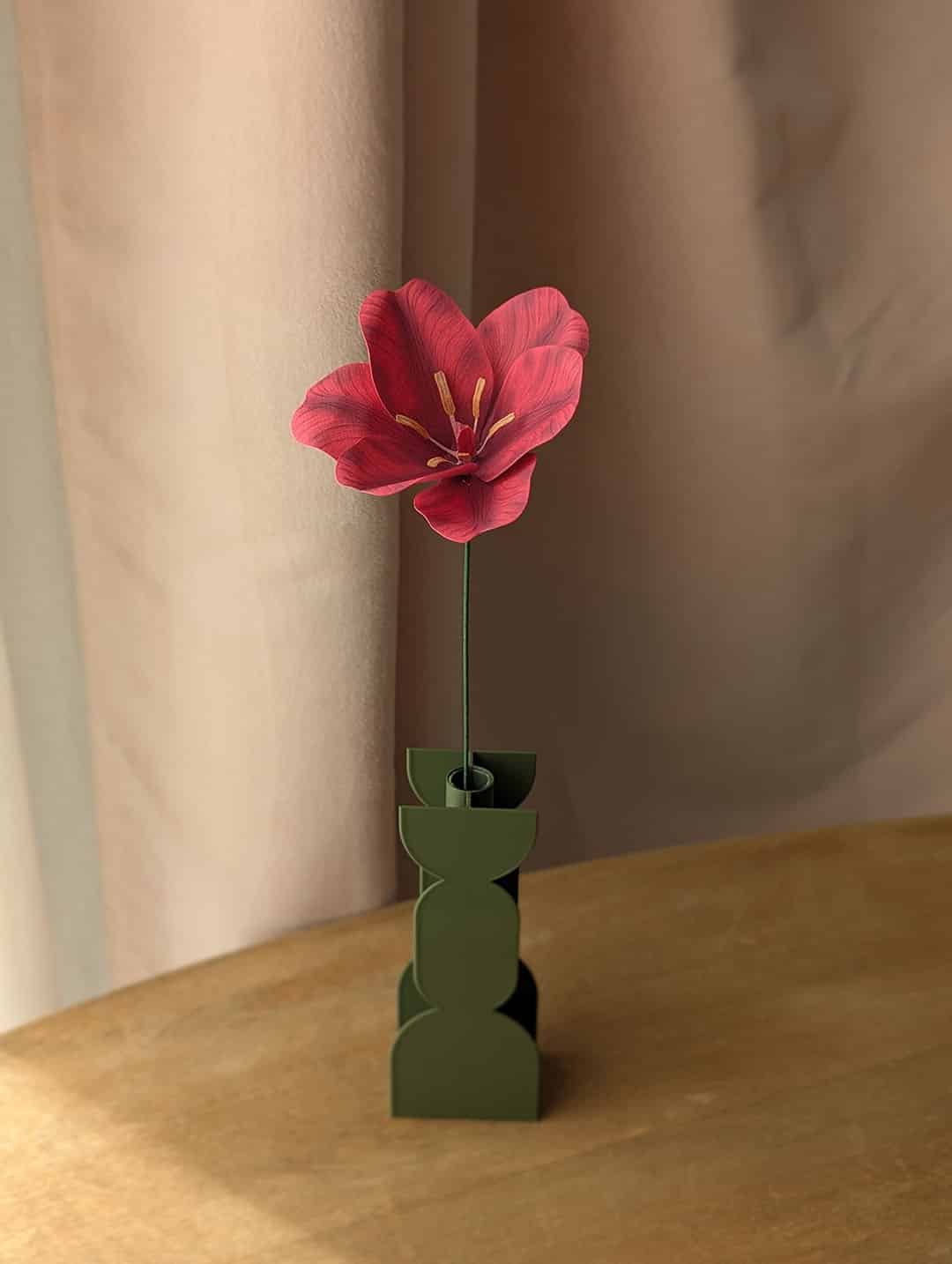 Tulipe ouverte en papier coloris fuchsia dans un vase vert sur une table en bois