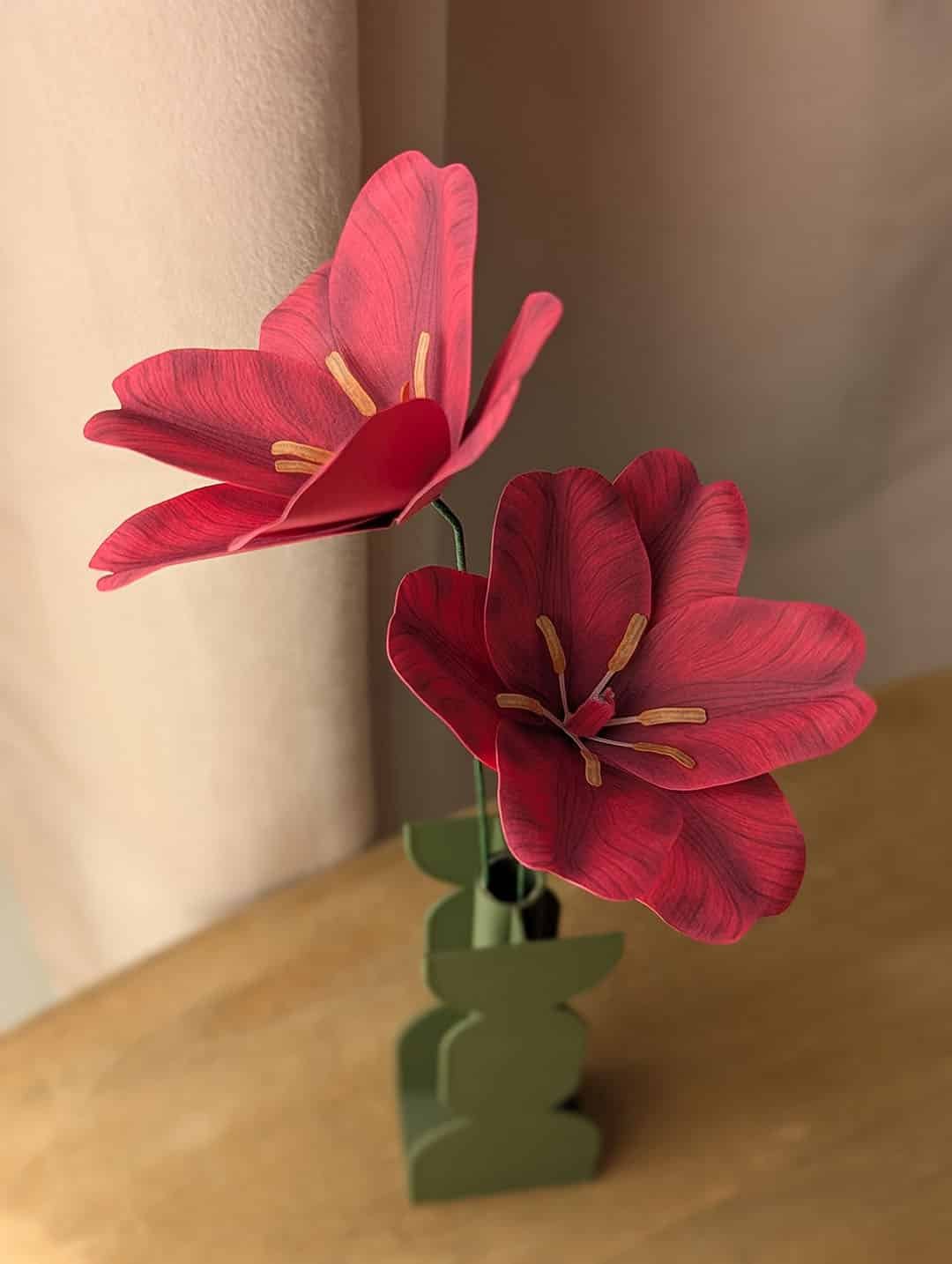 Gros plan sur deux tulipes ouvertes en papier fuchsia sur une même tige