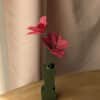 Deux tulipes ouvertes en papier fuchsia dans un vase coloris vert sur une table en bois